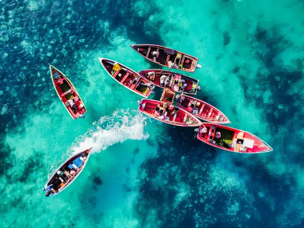 Vista aérea de barcos de pesca coloridos em águas cristalinas