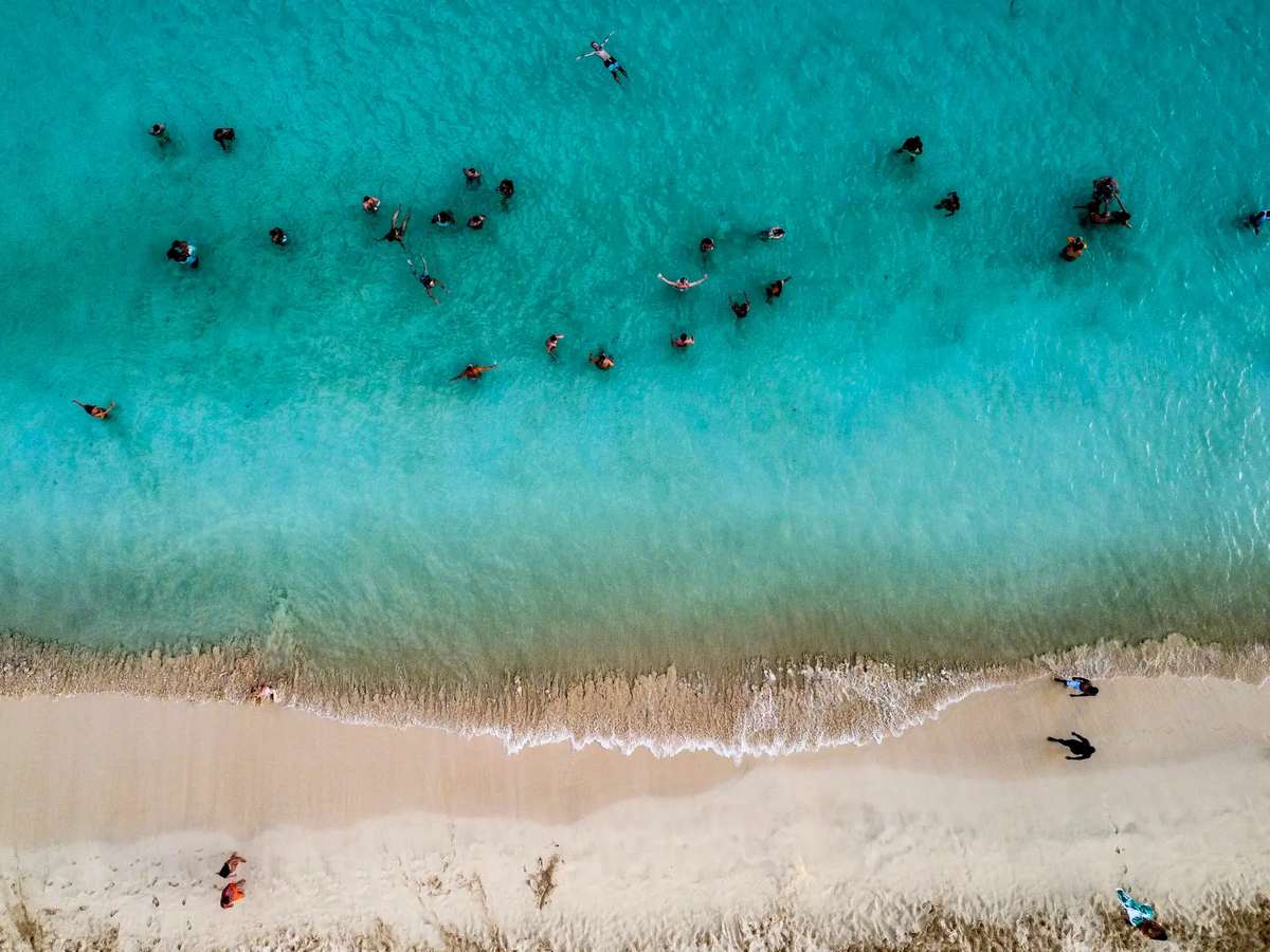 Vista aérea da praia de Santa Maria com banhistas nas águas turquesa