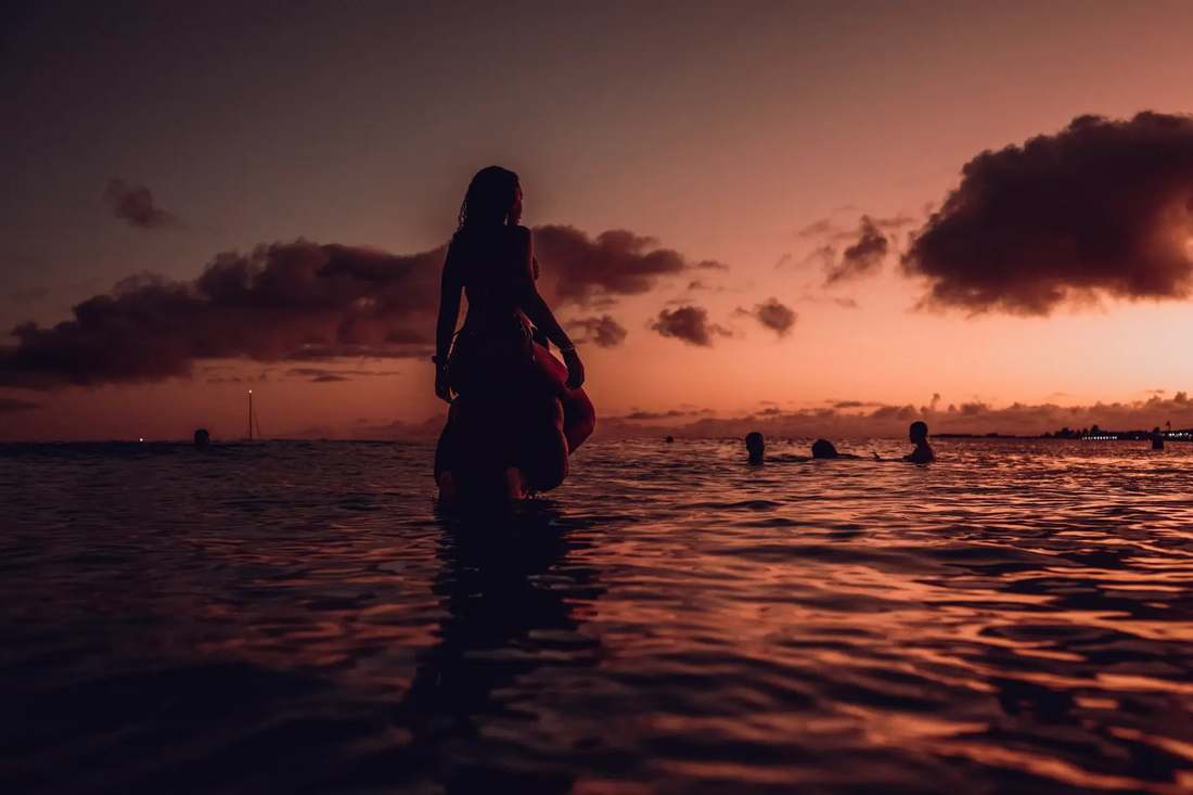Silhueta de uma hóspede a entrar tranquilamente no mar ao entardecer, Ilha do Sal